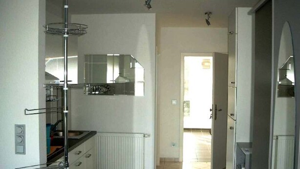 A modern kitchen with a built-in oven, a microwave, and a stainless steel refrigerator. There is a window providing natural light and a door leading to a hallway. - Vacation apartment on Lake Mirower See (without balcony) right Whg.3 - Ferienwohnungen am See (Mirow)