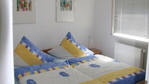 A single bed with a wooden frame, a quilt with blue and yellow patterns, and two framed artworks on the wall. - Vacation apartment on Lake Mirower See (without balcony) right Whg.3 - Ferienwohnungen am See (Mirow)