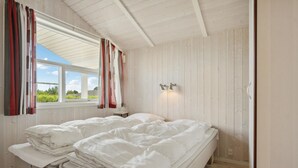 A room with a bed, a window with curtains, and a wall-mounted light fixture. - Beach front home in Rudkøbing with sauna (Rudkøbing)
