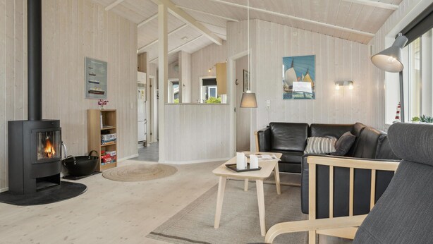 A cozy living room with a fireplace, a sofa, a coffee table, and a dining area. - Beach front home in Rudkøbing with sauna (Rudkøbing)
