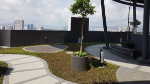 A rooftop garden with a circular pathway, a potted tree, and a view of the city skyline. - MZ Homestay Kuala Lumpur (Kuala Lumpur)