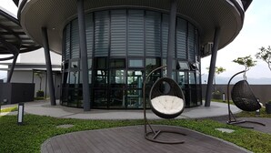 A modern building with a circular design, large windows, and outdoor seating areas with hanging chairs. - MZ Homestay Kuala Lumpur (Kuala Lumpur)