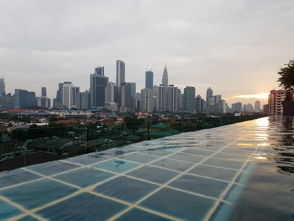 A cityscape with modern high-rise buildings and a reflective pool in the foreground.