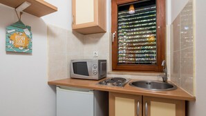 Una cucina compatta con forno a microonde, lavello e mobili in legno.