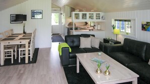A modern living room with a black leather sofa, a wooden coffee table, and a dining area with a wooden table and chairs. - Nice home in Jægerspris with WiFi (Jægerspris)