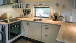 A modern kitchen with a built-in oven, a stainless steel sink, and a window with blinds. - Nice home in Jægerspris with WiFi (Jægerspris)