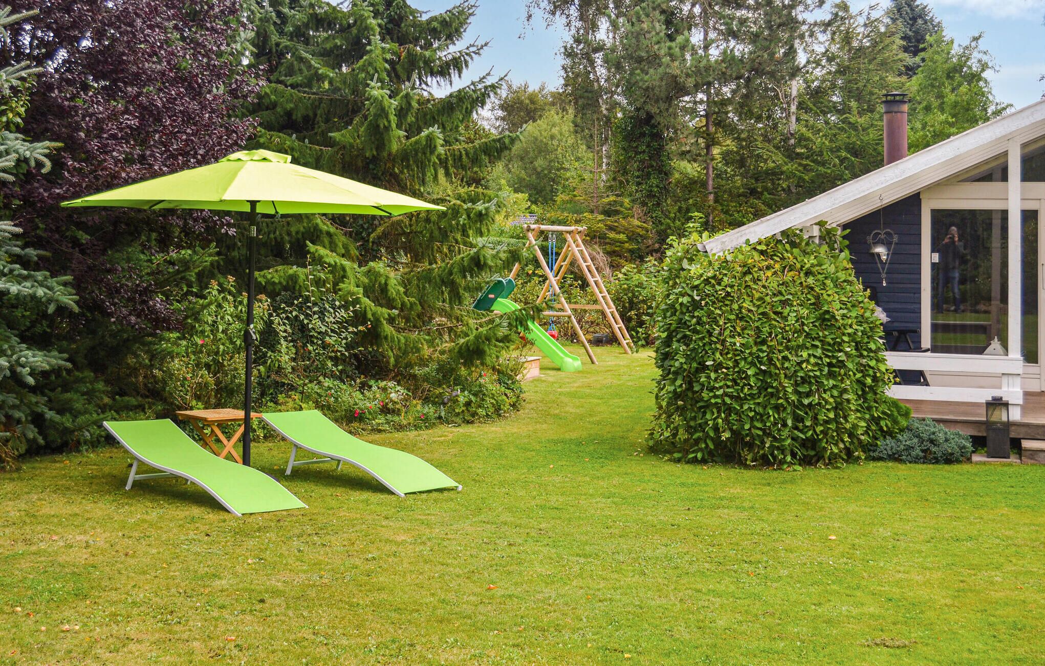 A backyard with a swing set, a slide, and a green lawn.
