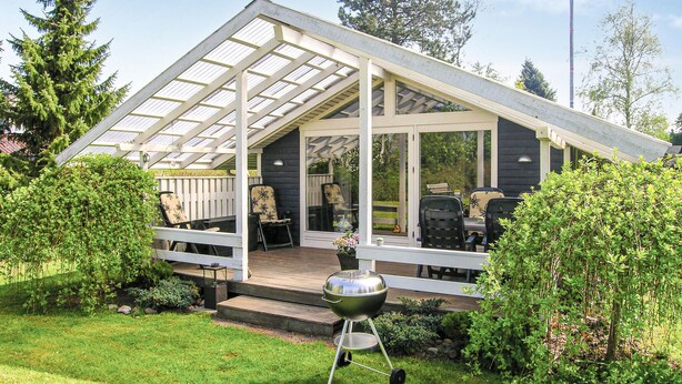 A covered patio with outdoor seating, a grill, and a view of the surrounding garden. - Nice home in Jægerspris with WiFi (Jægerspris)