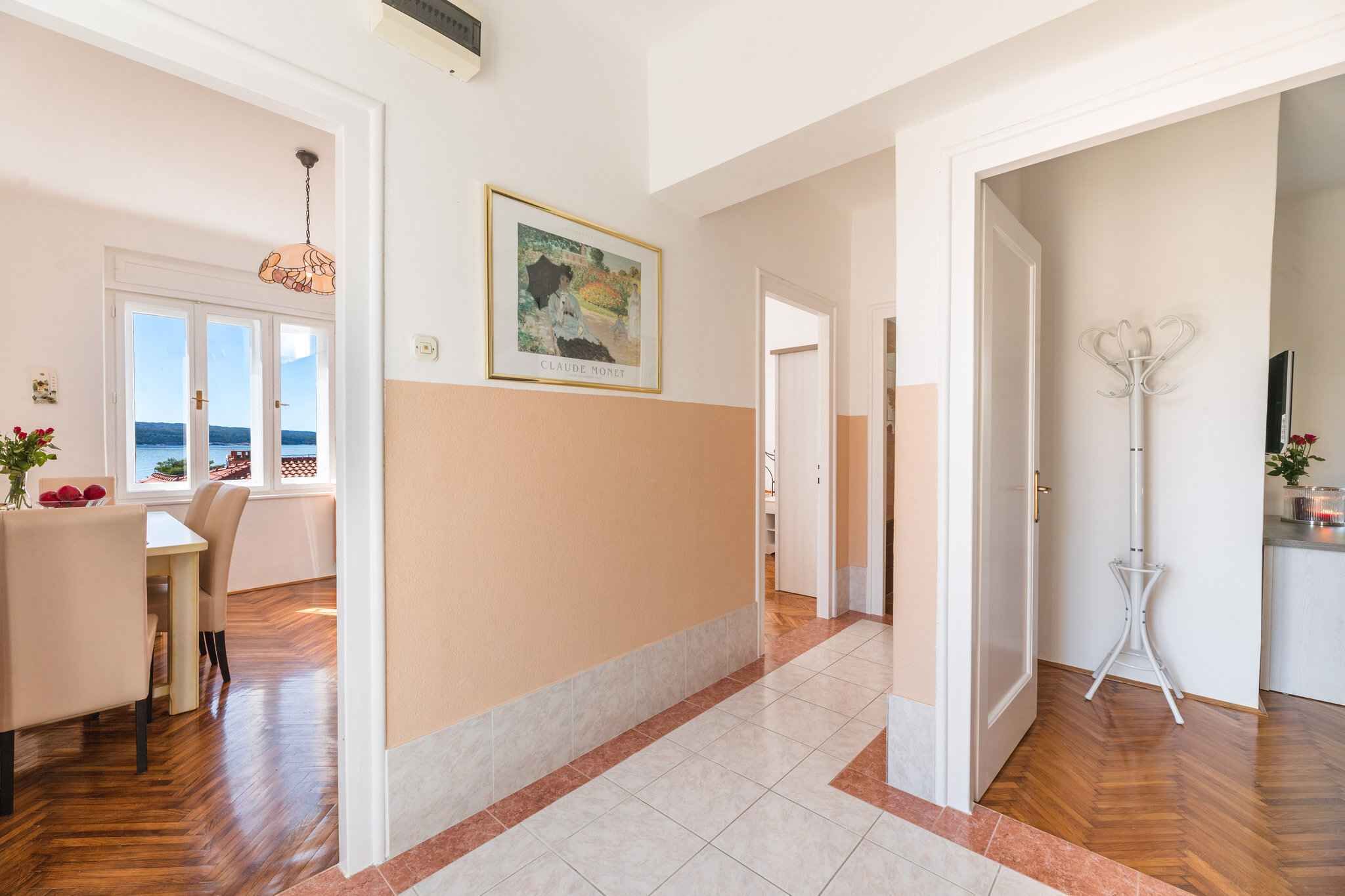 Un salón amplio con una mesa de comedor, una lámpara blanca y una obra de arte enmarcada en la pared.