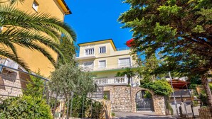 A yellow building with a balcony and a stone wall.