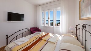 A bedroom with a bed, a television, a chair, a window with a view, and a lamp.