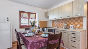 Una cucina compatta con mobili in legno, zoccolo piastrellato e angolo ristoro con tavolo apparecchiato per due.