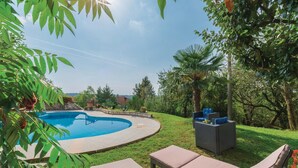 Un giardino con piscina, poltrona relax e tavolino in vimini.