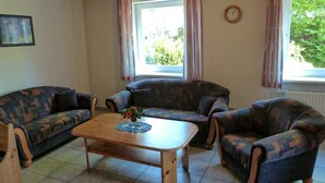 Ein Wohnzimmer mit zwei gemusterten Sofas, einem Holztisch und einer Uhr an der Wand.