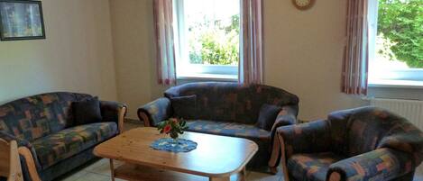 A living room with two patterned sofas, a wooden coffee table, and a clock on the wall.