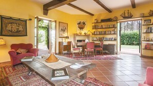 Een gezellige woonkamer met een houten tafel, boekenplanken en een rode fauteuil.
