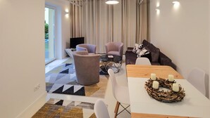 A modern living room with a sofa, armchairs, a coffee table, and a dining table with candles. - 4 bedroom cozy home in Grzybowo (Grzybowo)