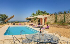 Ein Schwimmbecken mit Liegestühlen und einem Tisch mit Getränken, umgeben von Steinmauern und Blick auf das Meer.