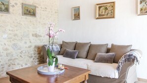 Una sala de estar con pared de piedra, un sofá, una mesa de centro y cuadros enmarcados.