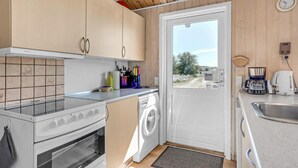 Cocina compacta con lavadora, cafetera y lavamanos.