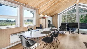 Un comedor moderno con una mesa grande, sillas negras y techo de madera.