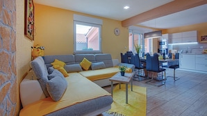 A living room with a sofa, a dining area with chairs, a kitchen with cabinets, and a clock on the wall. - Awesome home in Betiga (Betiga)