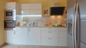 A modern kitchen with white cabinets, a microwave, oven, and a refrigerator. - Awesome home in Betiga (Betiga)