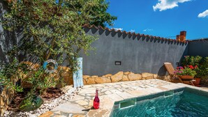 A poolside area with a stone patio, a small pool, and a wall with a tiled roof. - Awesome home in Betiga (Betiga)