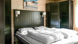 Un dormitorio con cabecera de madera, dos lámparas de noche y una cama con ropa blanca.