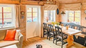 Un interior acogedor de cabaña con una mesa de comedor de madera, sillas, un sofá y un perro.