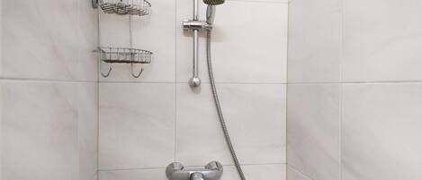 A shower area with a handheld showerhead, a fixed showerhead, and two metal shower trays.