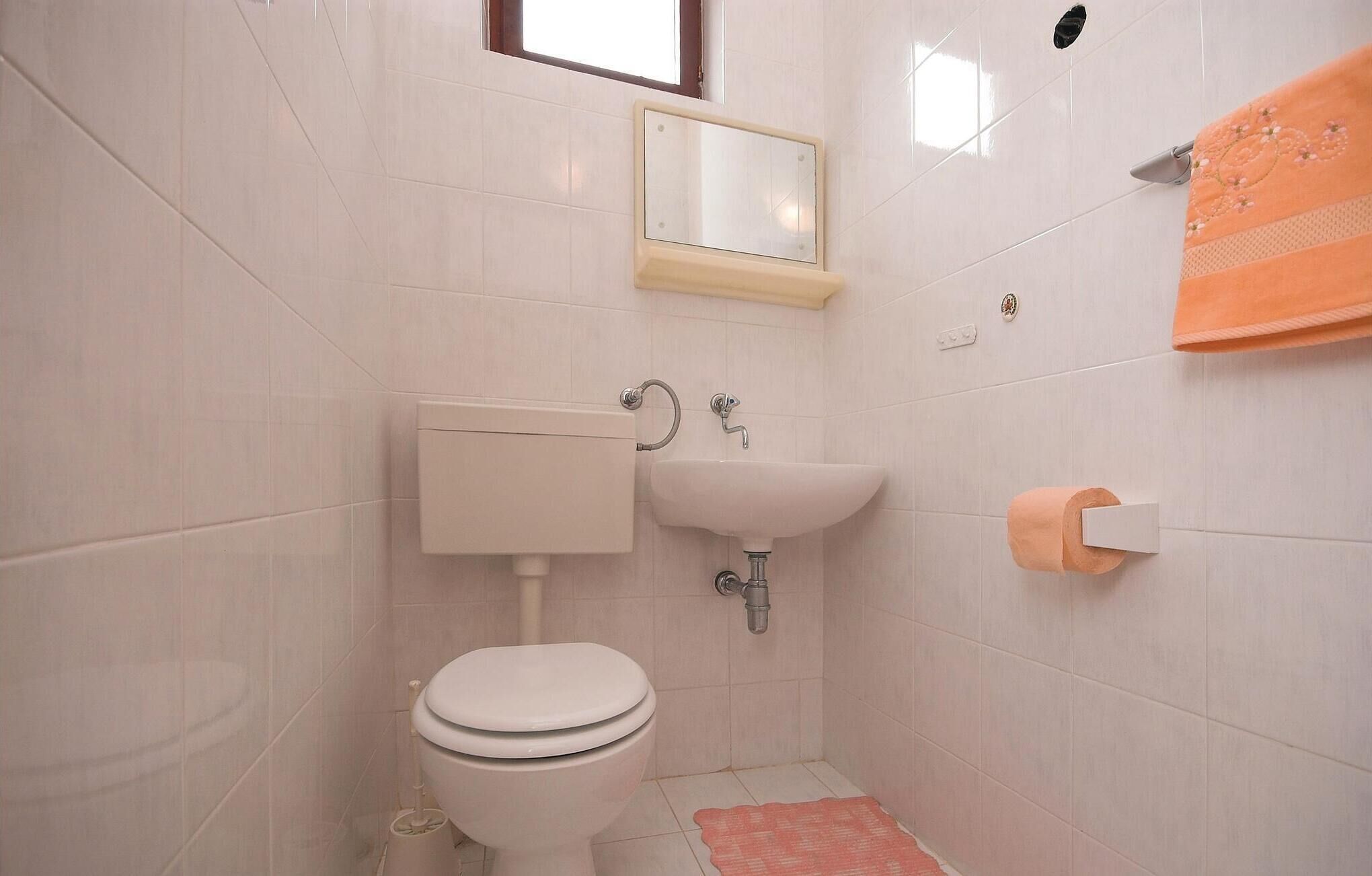 Une petite salle de bain propre, équipée de toilettes, d’un lavabo et d’un miroir.