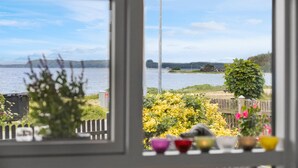 A view through a window with a wooden fence, a bench, and colorful bowls on a table. - Nice home in Rønde with WiFi (Rønde)
