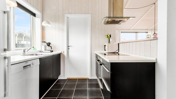 A modern kitchen with a white and dark wood color scheme, featuring a Siemens dishwasher, a coffee maker, and a microwave.