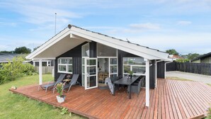 A modern house with a wooden deck, a dining area, and a covered patio with seating. - Nice home in Rønde with WiFi (Rønde)