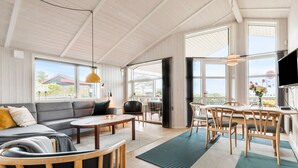 A spacious living area with a sofa, coffee table, and dining table, large windows, and a view of the outdoors. - Nice home in Rønde with WiFi (Rønde)