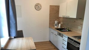 A small kitchen with a wooden table and chairs, a coffee maker, and a sink. - Apartment Type 1 - Meutzner Trassenheide, "Villa Seute Deern" (Trassenheide)