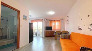 Ein Wohnzimmer mit Sofa, Fernseher und Balkon mit Blick.