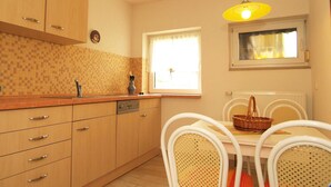 Una cocina con armarios de madera, un lavabo y un comedor con mesa y sillas.