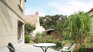 A patio with a round table and two chairs, surrounded by a garden with various plants and a fence. - Fritz-Reuter-Str. 10a. Curr. FR-10 - Fritz-Reuter-Str. 10a (Kühlungsborn)