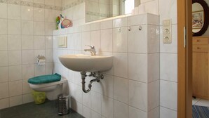 A bathroom with a white sink, a toilet, a trash can, and a mirror. - Fritz-Reuter-Str. 10a. Curr. FR-10 - Fritz-Reuter-Str. 10a (Kühlungsborn)