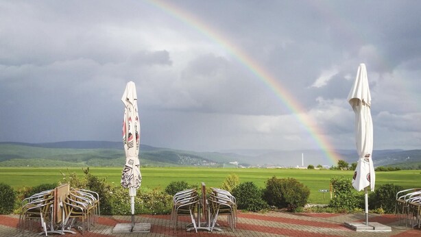 Ein Blick auf ein Restaurant mit Außenbereich und einem Regenbogen im Hintergrund.