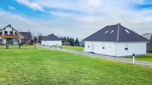 Ein Wohngebiet mit zwei weißen Häusern, eines davon hat einen Balkon und das andere ein Schrägdach.