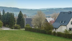 Ländliche Landschaft mit einem Haus, das ein geneigtes Dach und einen kleinen Anbau hat.