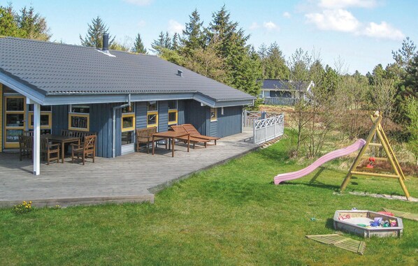 A two-story building with a covered patio area, outdoor seating, and a playground with a slide.