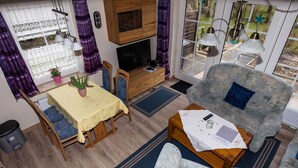 Een gezellige woonkamer met een bank, een eettafel en een televisie.