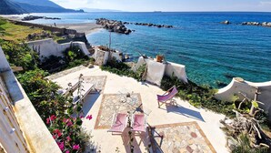 A coastal terrace with stone flooring, outdoor seating, and a view of the sea and distant mountains. - 3 bedroom beautiful home in Scilla (RC) (Scilla (RC))