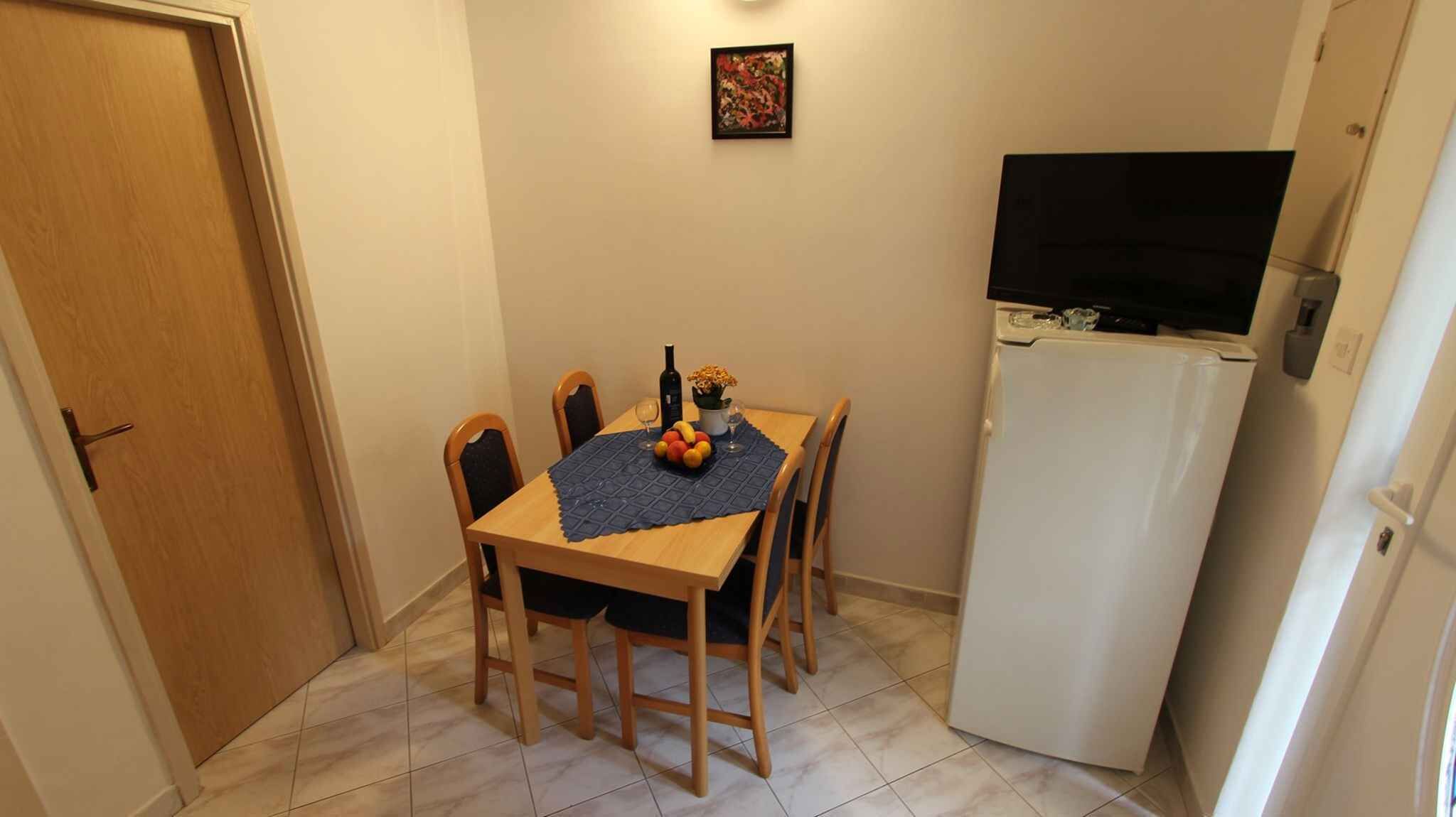 Un petit coin repas avec une table dressée pour deux personnes, un réfrigérateur et une porte.