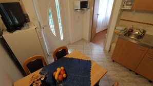 Kompakti keittiö, jossa on mikroaaltouuni, pesuallas ja ruokailutila, jossa on pöytä kahdelle.