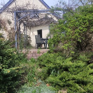 A garden with a table and chairs, a stone wall, and dense foliage.